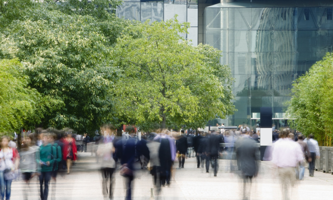 people in a blur among urban buildings and trees