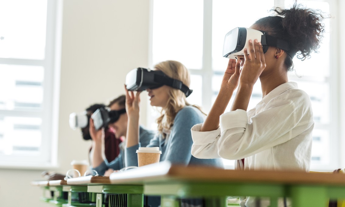 Fire personer sitter i et klasserom med VR-briller på.
