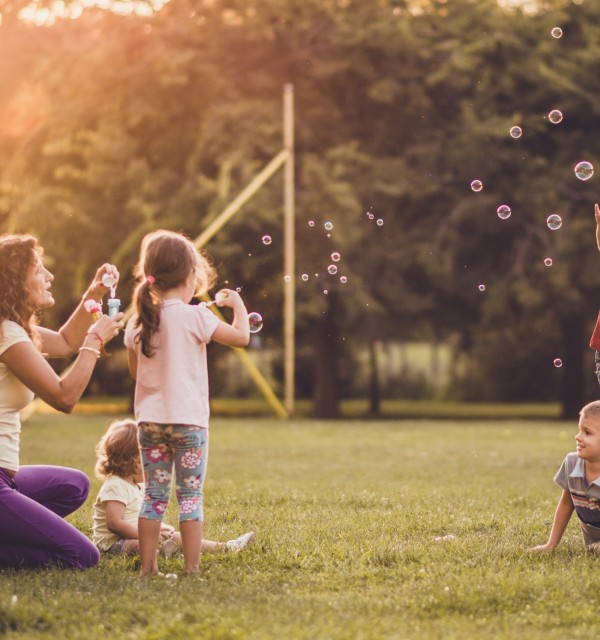 Barn og voksne som leker med såpebobler i en park.