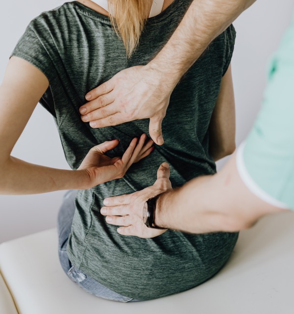 En kvinnelig pasient viser behandler hvor på ryggen hun har vondt.