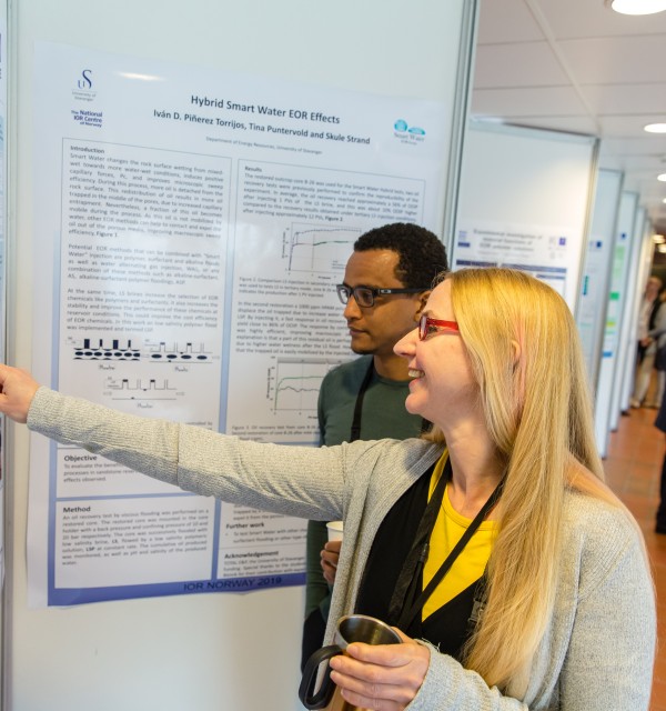 En kvinne viser fram forskningen sin på en poster