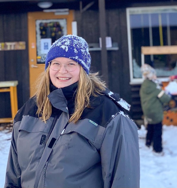 Ung kvinnelig barnehagelærerstudent er i praksis i barnehage. Uteområde, snø.