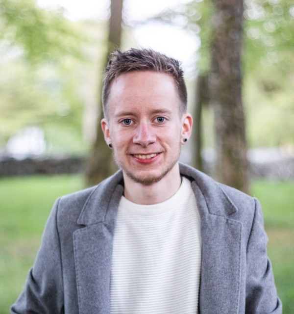 Ung mann med hvit genser og grå jakke