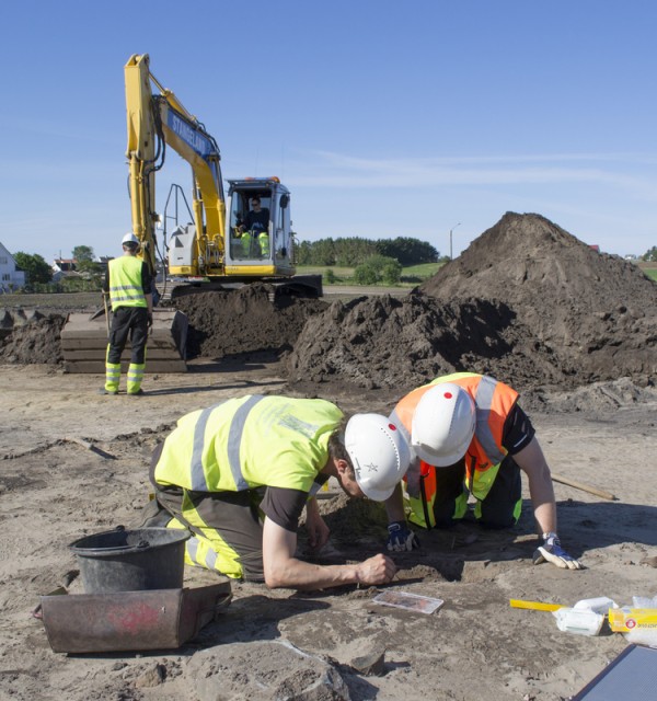 To arkeologer fra Arkeologisk museum på utgravingsfelt - tar ut funn i preparat