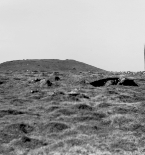 Svart-hvitt foto av kupert landskap med et steingjerde i bakgrunnen