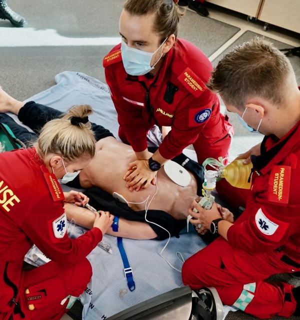 Simulering ved HelseCampus. Tre studenter i rød uniform.
