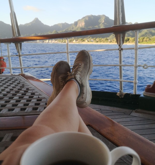 Kaffekopp og hvilende bein på seildekk