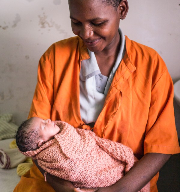 Tanzaniansk kvinne med nyfødt barn i armene 