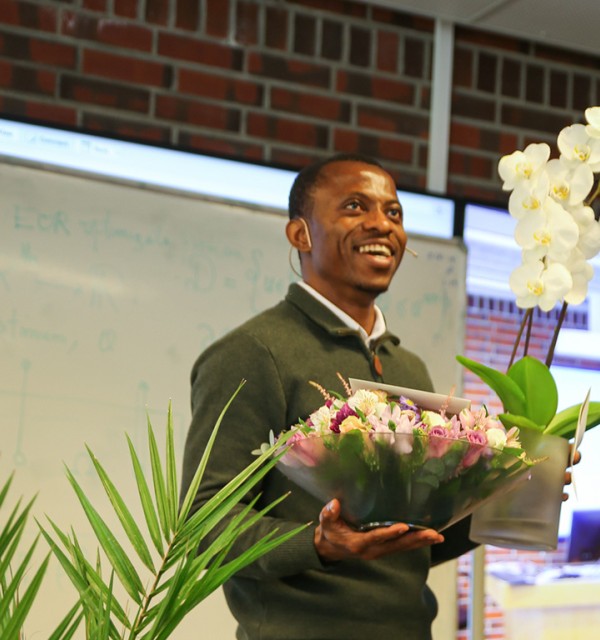 En mann står på en scene med hendene full av blomster.