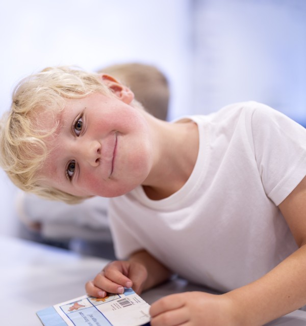 En gutt sitter ved et bord og smiler til kamera. Foto: Elisabeth Tønnessen/Læringsmiljøsenteret, UiS
