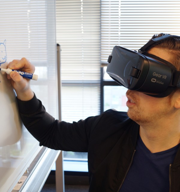 Mann med VR-briller skriver på en tavle