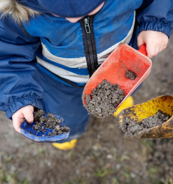 barnehender som holder spader med våt sand, 