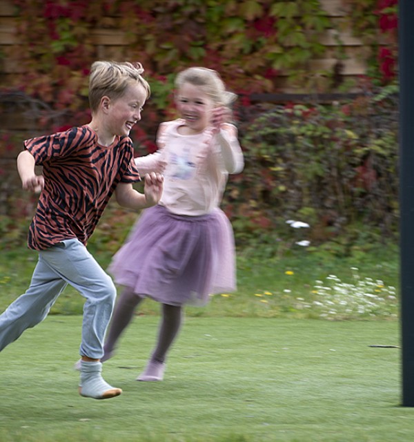 Jente og gutt løper i glad lek.