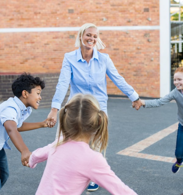 Voksen leker ringlek utendørs med barn på SFO