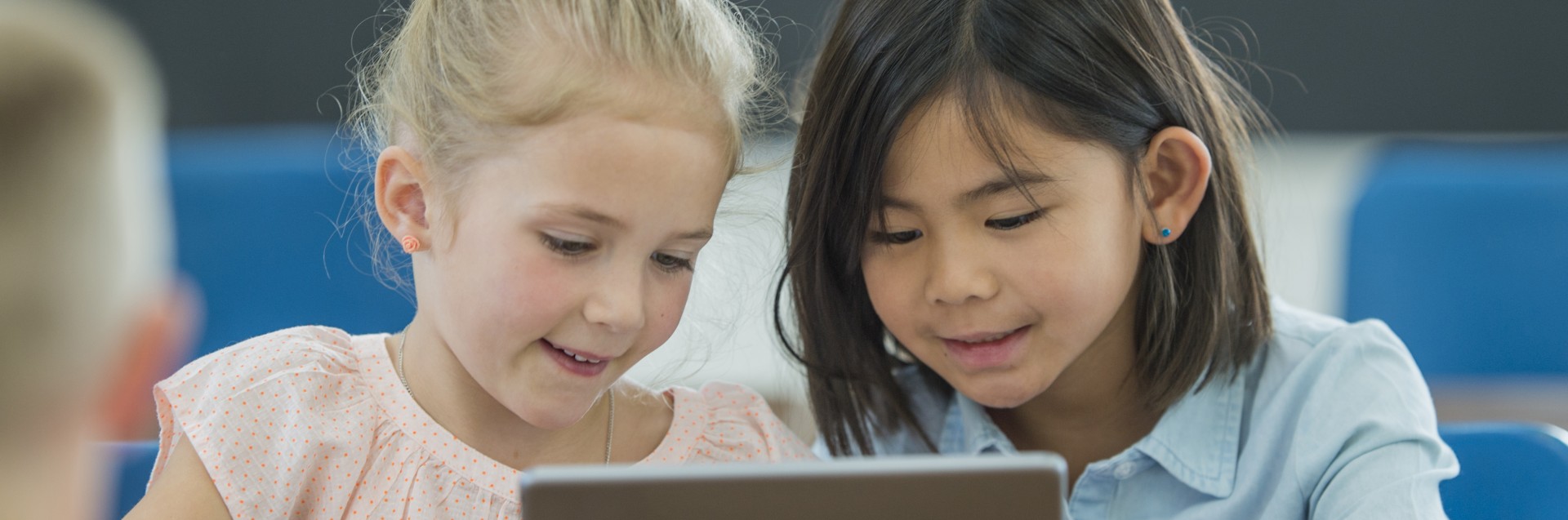 To små jenter ser på en ipad sammen i et klasserom