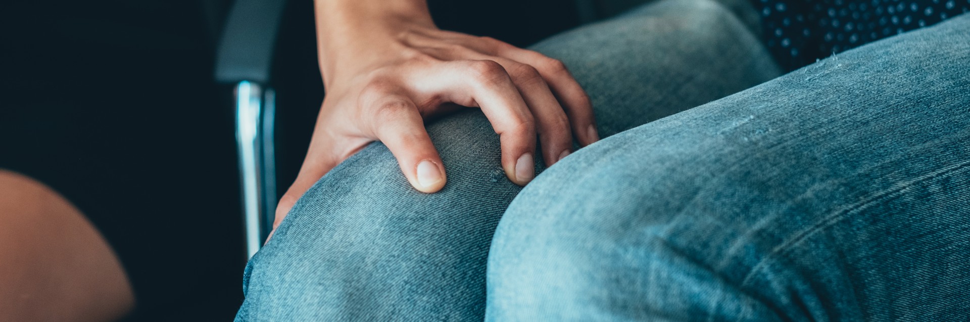 Utsnitt av en kvinnehånd som har et grep rundt låret til en annen person. Utsnittet viser kun øvre del av beina til denne personen. 