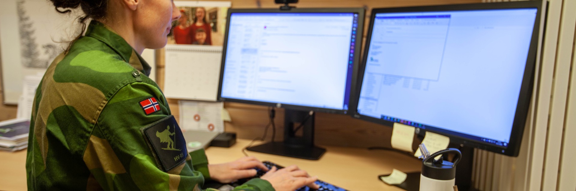 Kvinnelig soldat i Heimevernets uniform jobber foran en pc