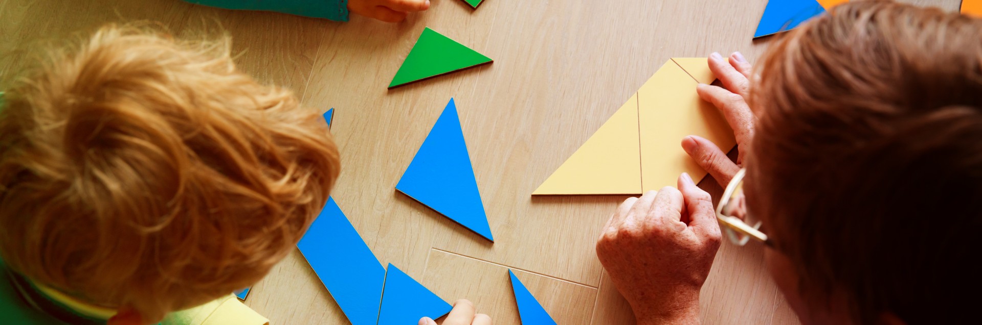 To barn og en voksen setter sammen biter av ulike geometriske former