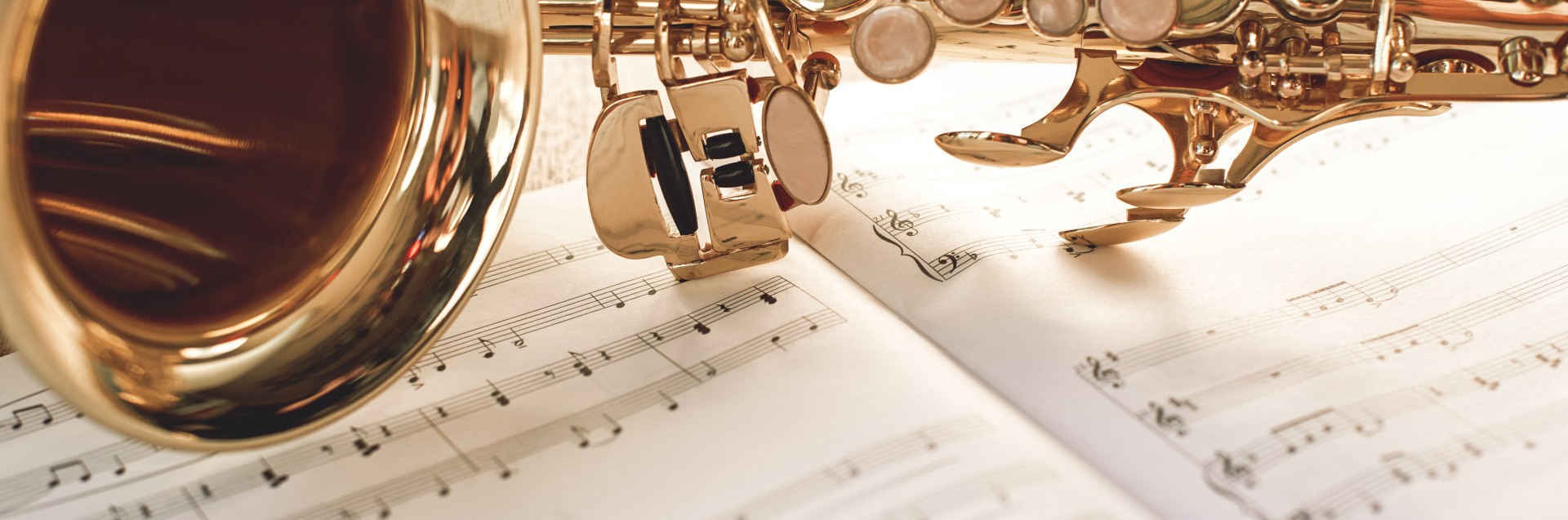 Nærbilde av en gyllen saksofon liggende på musikknoter