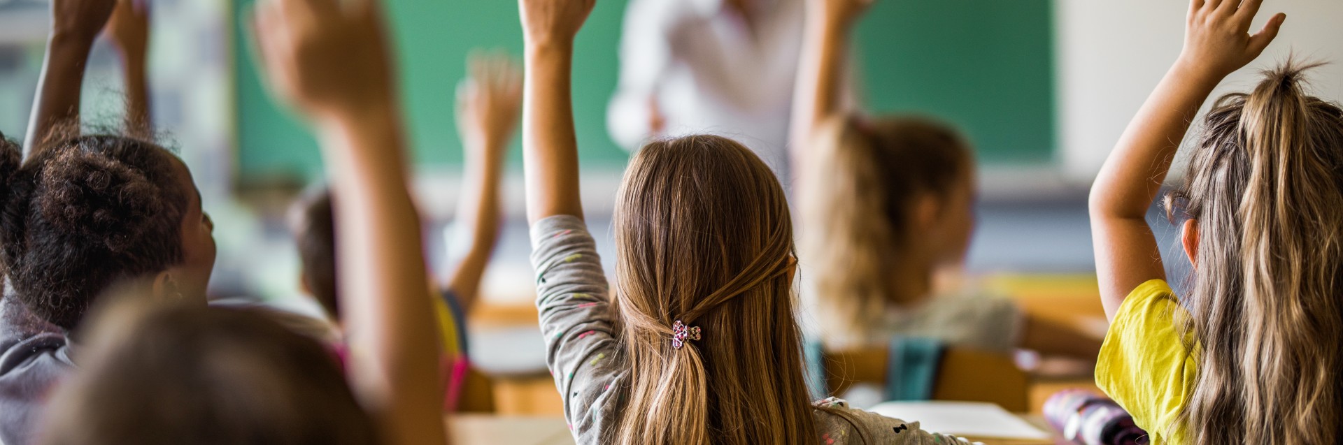 Barn i et klasseom rekker opp hendene