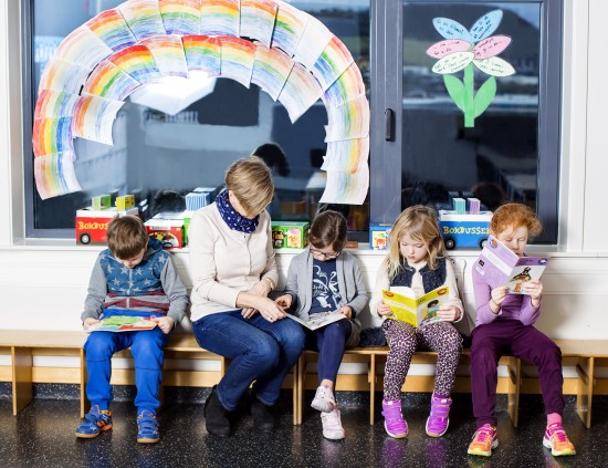 Fire elever og en lærer sitter på en benk og leser.