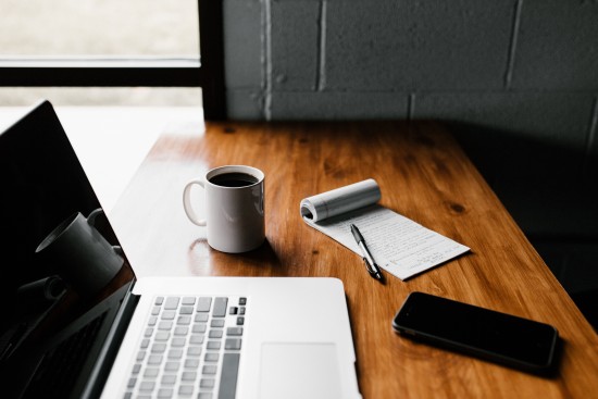 Et bord med en laptop, mobil, kaffe og notatblokk - illustrasjon på studiehverdag