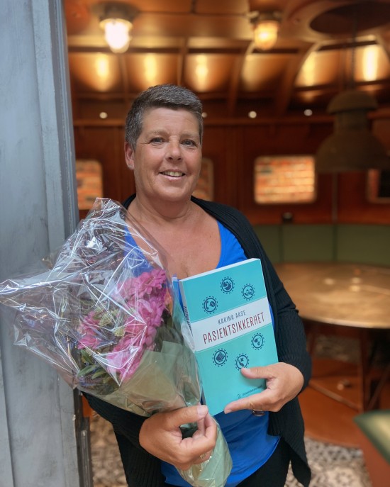 Bildet viser bokens kvinnelige forfatter som holder bok og blomster.