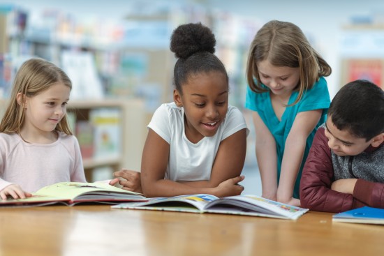 fire barn leser bøker ved bord