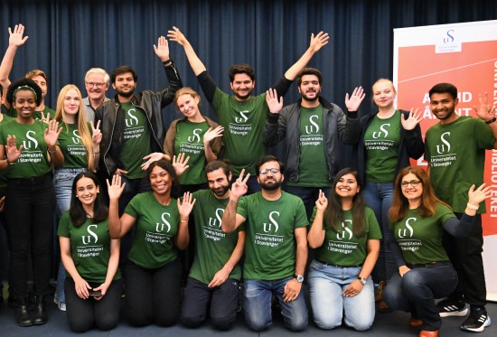 15 studenter med grønne UiS-t-skjorter jubler og vifter med armene