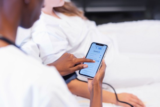Sykepleierstudent bruker øvingsapp på telefonen til å trene på praktiske prosedyrer