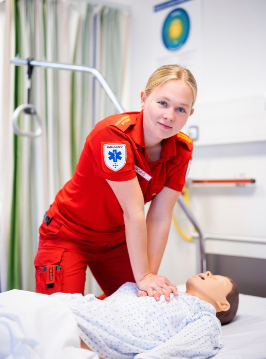 Paramedisinstudent utfører hjerte- og lungeredning på en simuleringsdukke i øvingslaboratorium.