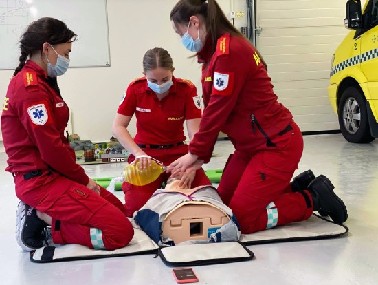 Bildet viser tre paramedisin-studenter som gjennomfører en øvelse.