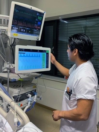 Bildet viser alumni-studenten foran et apparat på intensivavdelingen.