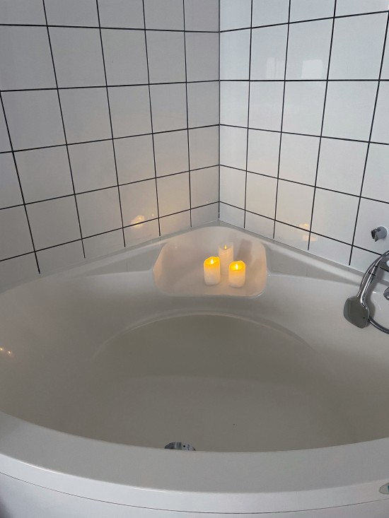 Bildet viser et badekar med tente lys på kanten. Ved vannfødsel ligger du i et badekar eller spesialkar under fødselen. Barnet fødes med hele kroppen sin under vann.