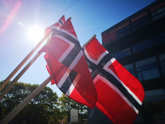 Three norwegian flags seen from below. Blocking the sun.