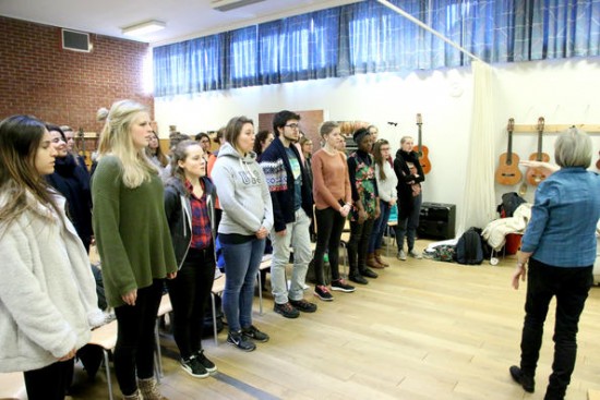 Mange internasjonale studenter som står i et klasserom og synger_bildet
