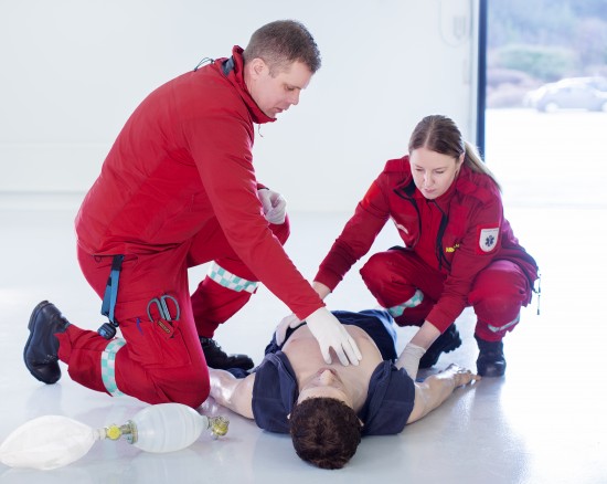 En mannlig og en kvinnelig paramedisiner i uniform øver på observasjon av pasient ved bruk av en simuleringsdukke