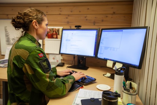 Kvinnelig soldat i Heimevernets uniform jobber foran en pc
