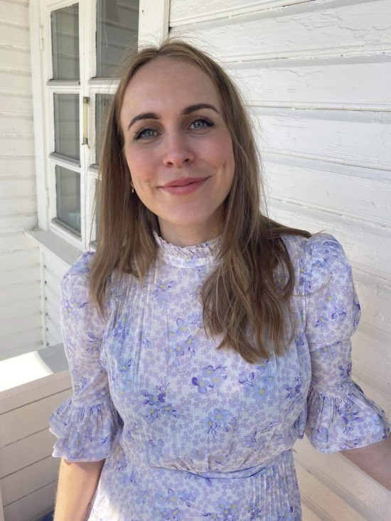 Portrett av smilende ung kvinne med langt hår i lys lilla kjole