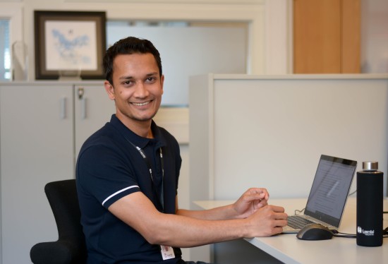 Navid jobber på PC'en og smiler til kamera