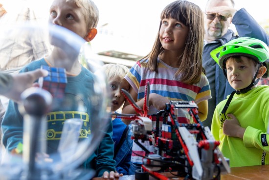 Fire barn i barneskolealder står foran en maskin som bygger legoklosser og en plasmalampe.