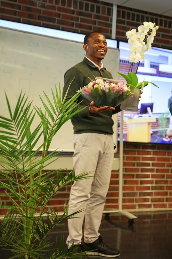 En mann står på en scene med hendene full av blomster.