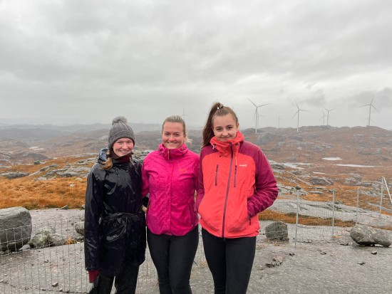 Studentane Ingrid Flood, Ragnhild Leidland og Maren Lovise Jåsund foran vindparken i Bjerkreim i grått vær
