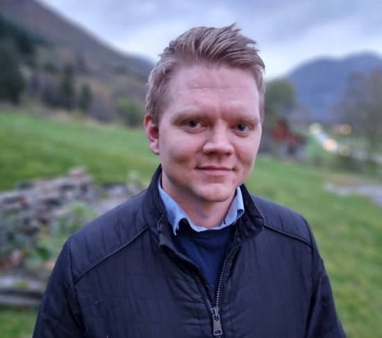 Portrettbilde av mann foran grønn gressbakke