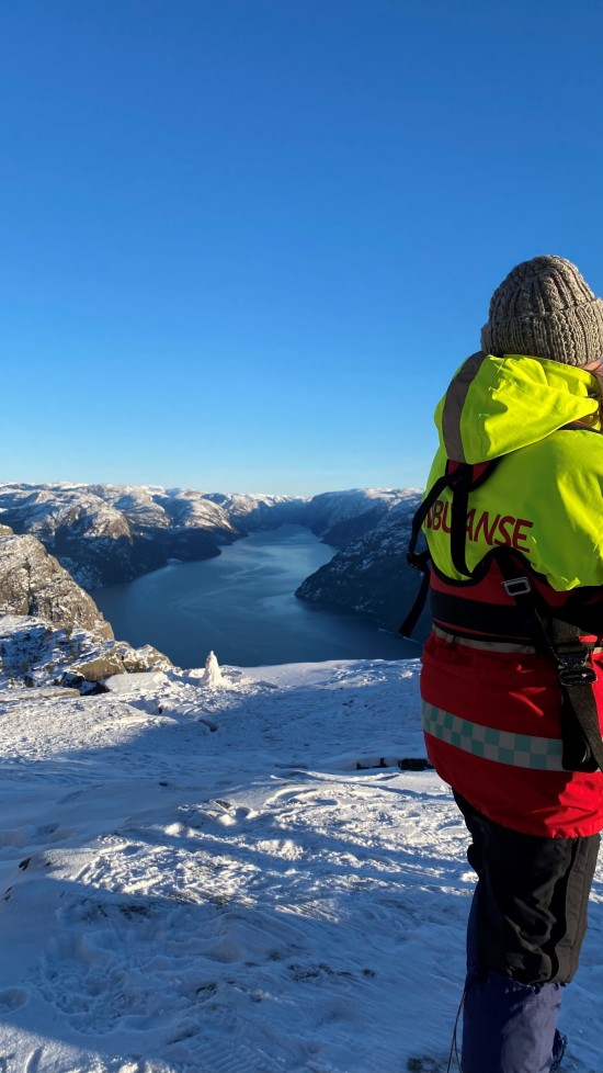 Ambulansearbeider på Preikestolen som ser utover Lysefjorden.