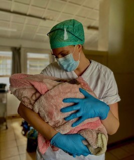 Helsepersonell som holder en nyfødt baby