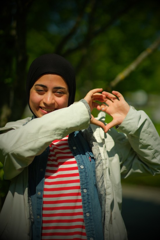 ung kvinne i hijab former et hjerte med hendene sine, smiler til kamera