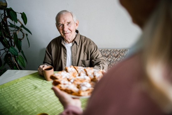 Eldre mann med kaffekopp blir servert bakst