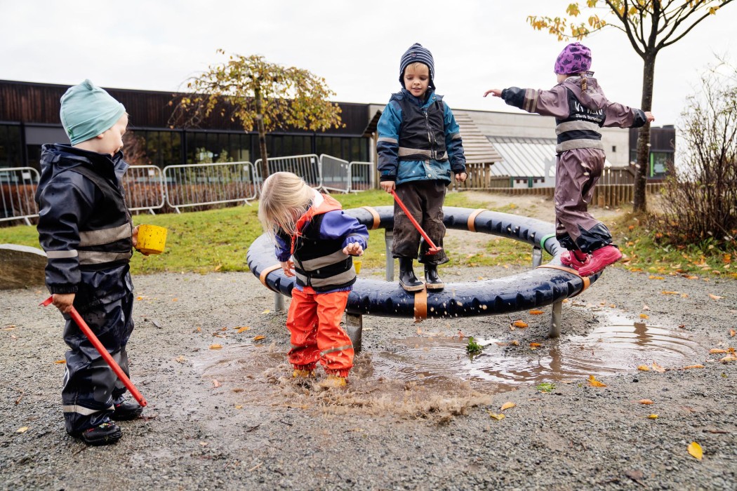 Fire barn leker utendørs en våt høstdag i Jåttå barnehage