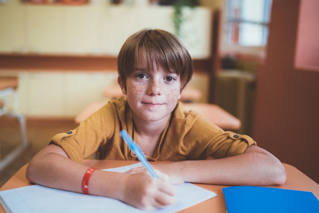 gutt i klasserom skriver med penn getty